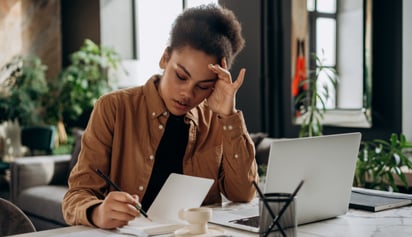 woman thinking and writing in a book